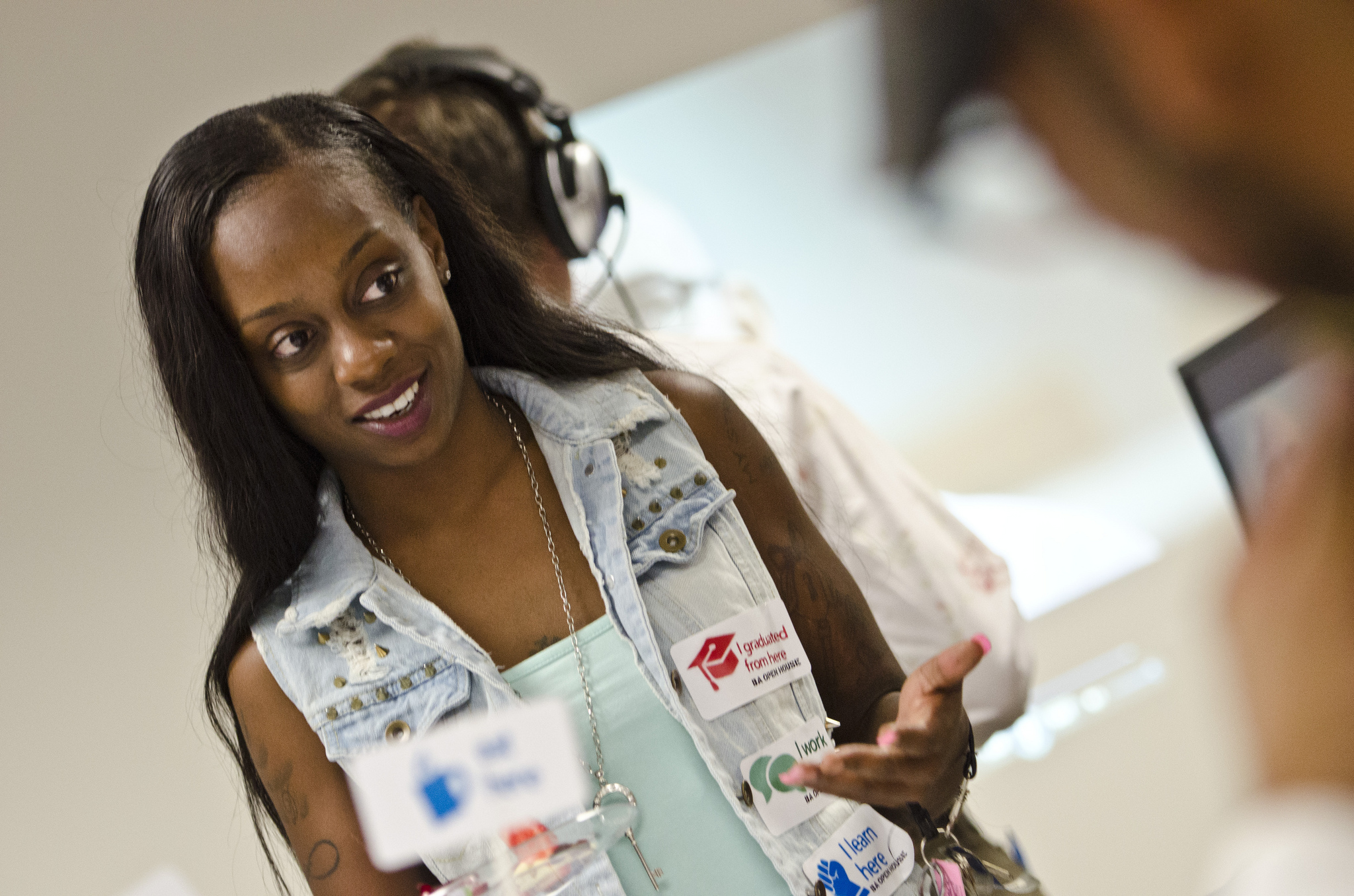 Very angled picture of young lady in class with lots of college advertisement pins on her vest