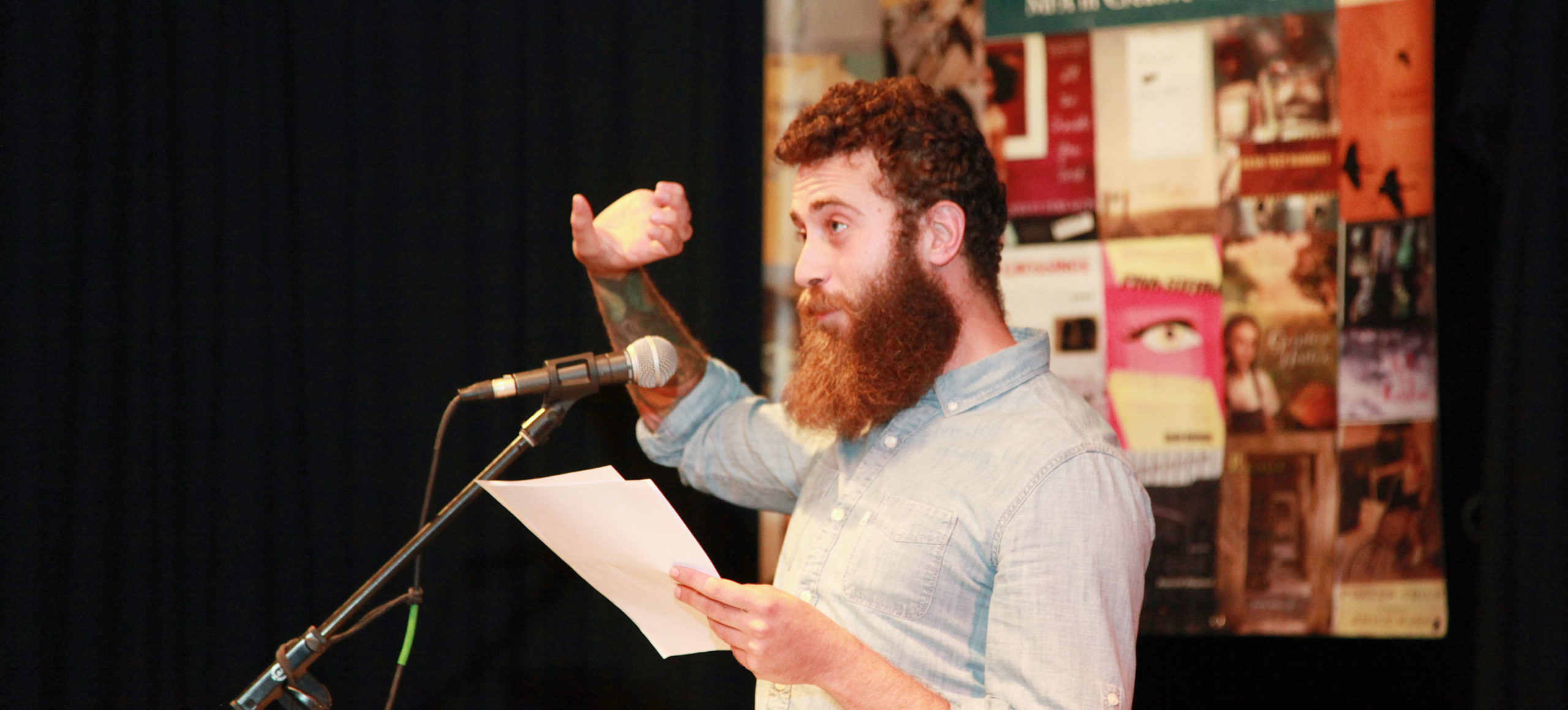 Man with long red beard speaking to crowd making a pouring something out hand gesture