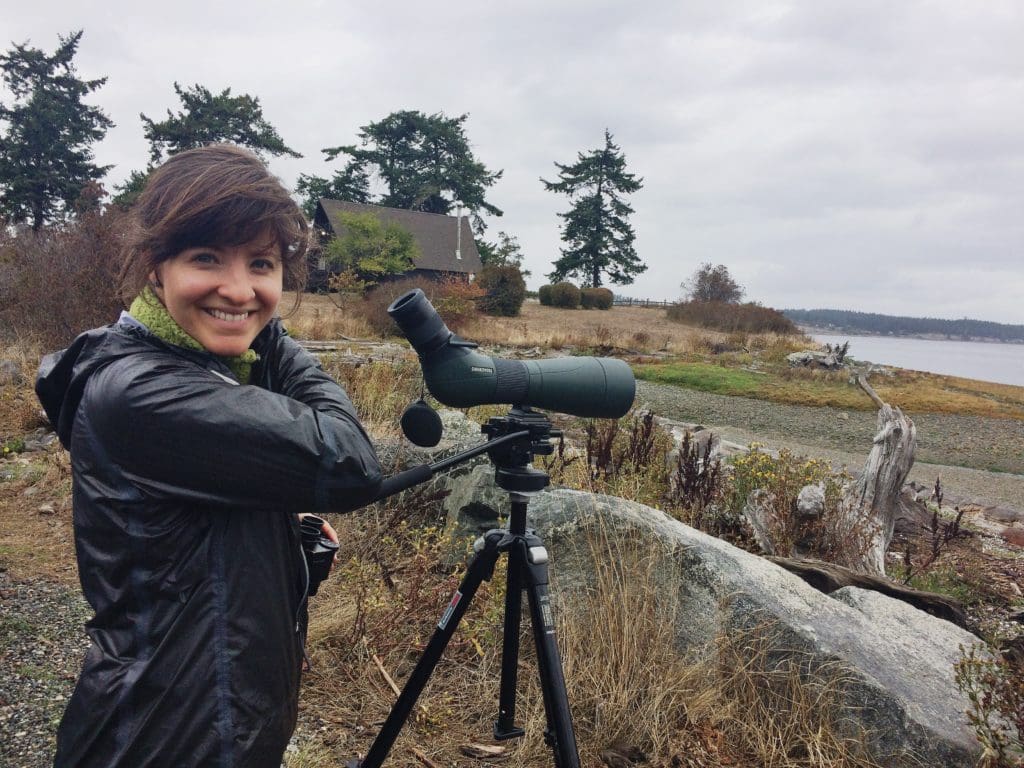 Woman smiling while looking through telescope