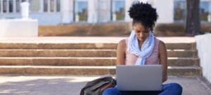 student working on laptop outside on stairs
