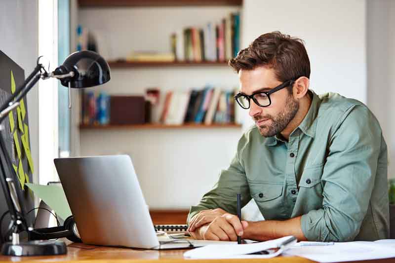 man working on laptop in green shirt and glasses