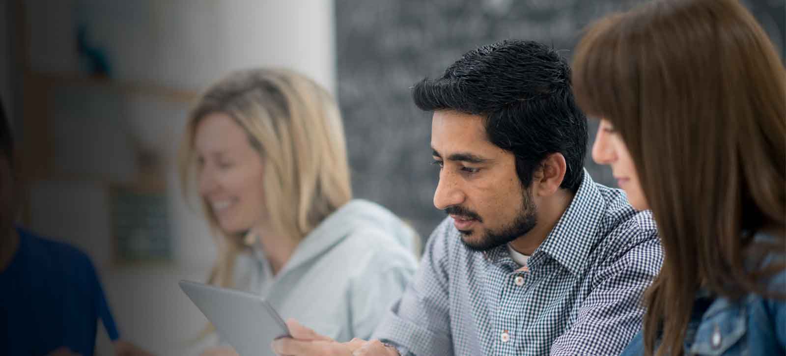 AU_Hero_EdD_4 › Antioch University man and woman talking doing classwork with classmates in background