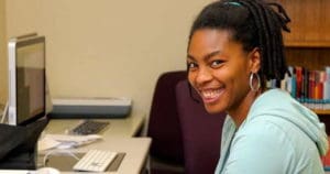 Individual smiling from computer at camera