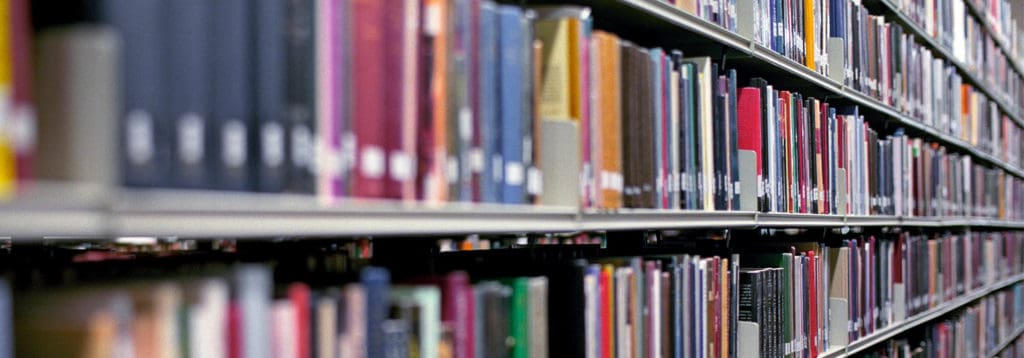A diminishing perspective of books stacked on metal shelves in a library setting