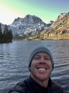 A portrait of Nate in front of mountains