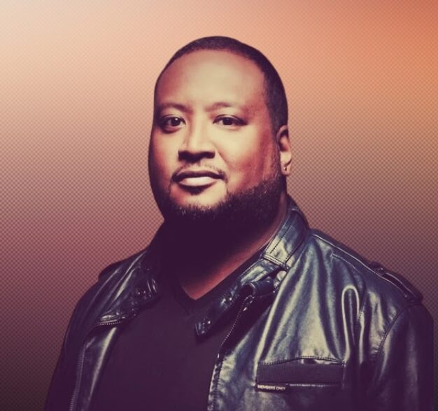 F Douglas Brown Antioch University F Douglas Brown man in black leather jacket black shirt orange background