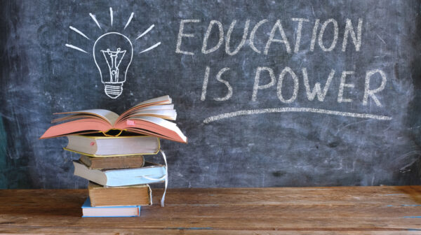 books and blackboard with drawing of a lightbulb and slogan education is power, learning, knowledge, back to school concept