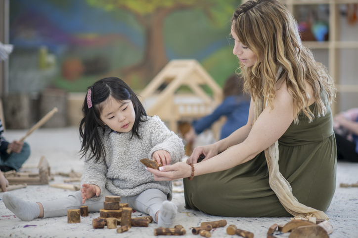 Waldorf elementary teacher and student building with wooden blocks