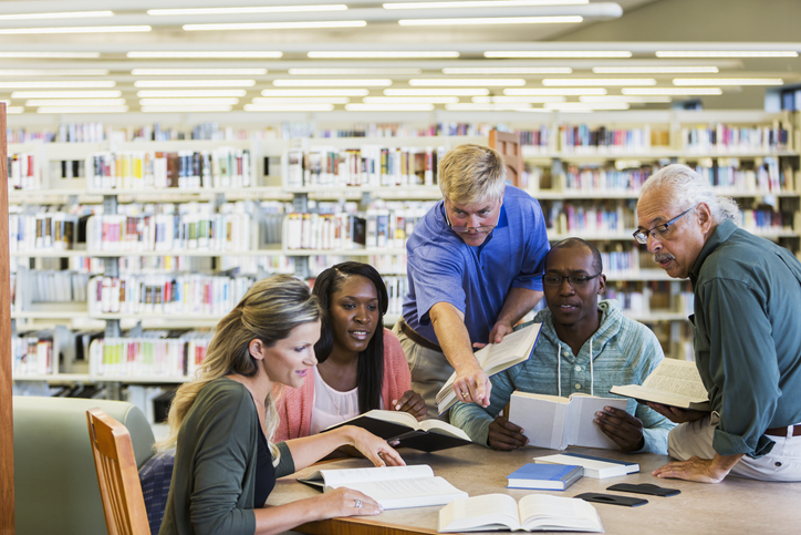 Adult students studying together in library