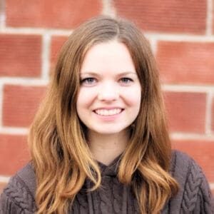 Allie smiling in front of a brick wall