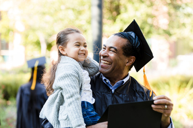 Person graduating holding diploma and smiling child.