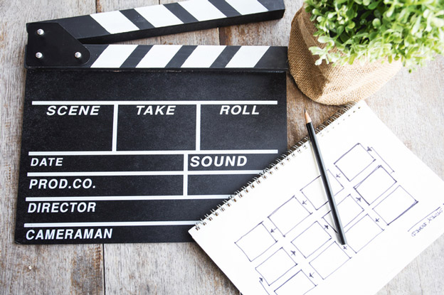 Clapper board and story board on a desk with a plant.