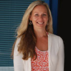 Jill Howe-Vercos, M.A., MFT- This image depicts a woman with long layered hair, wearing a white sweater and pink orange and white top and smiling at the camera.