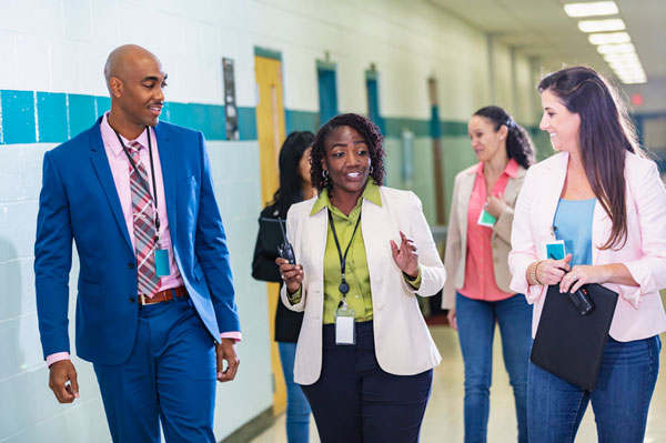 A group of 5 educators walking down a school hallway.