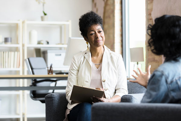 Psychologist working with a client. The client has their back to the camara.