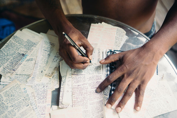 Person working on draft of writing, table is covered with hand written notes.