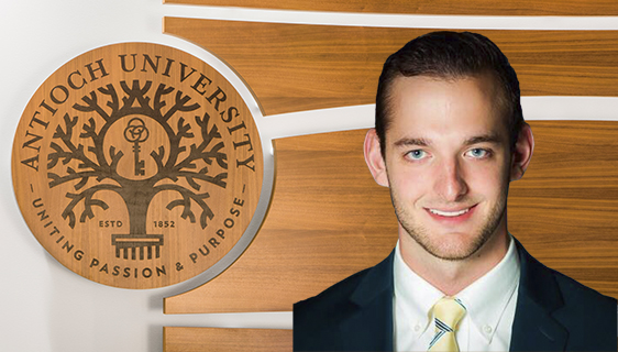 Admissions-Brett-Jones › Antioch University Portrait of Brett Jones in front of the Antioch University Seal