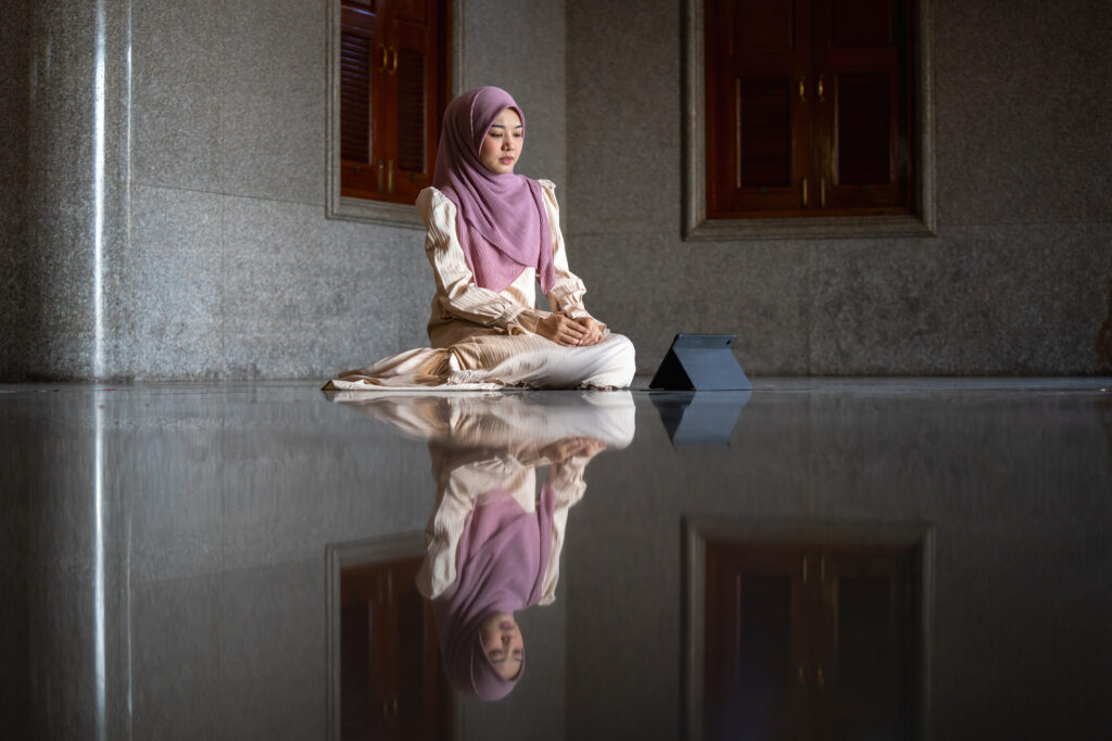 Close-up of a young Muslim woman using a tablet to read the Quran in a mosque › Antioch University