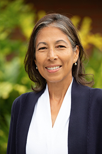 A portrait of Ana Gorman, a woman on a out of focus natural background smiling at the camera