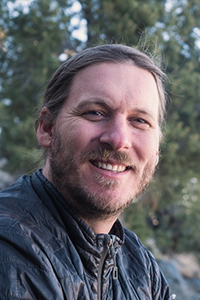 A portrait of Jasper Nighthawk, outdoors with an out of focus nature background. 