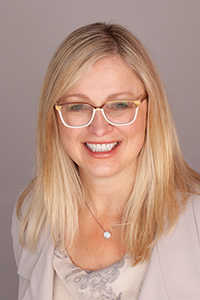 Portrait of Karen Hamilton, a woman, on a neutral background, smiling at the camera