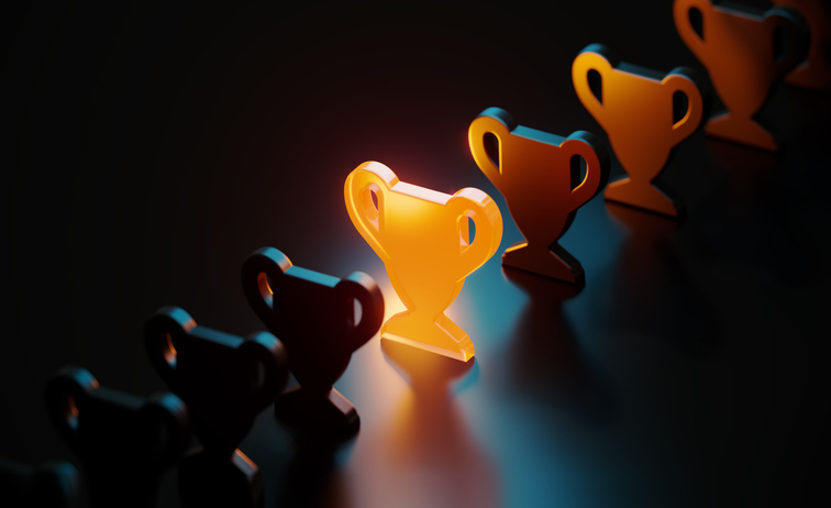 Row of trophy icons lined up, with the center trophy glowing in orange light representing achievement.