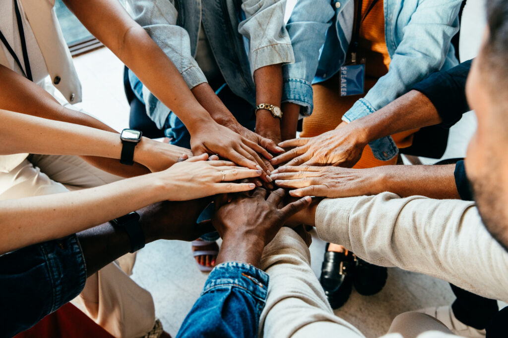 Teamwork concept with diverse hands joining together symbolizing unity cooperation and collaboration | Antioch University Group of diverse hands stacked in a circle, symbolizing teamwork and unity.