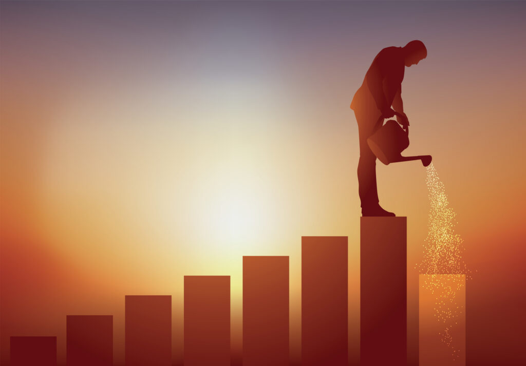 Concept of professional evolution with a man who cultivates his career plan by watering the walk that will allow him to move forward | Antioch University Two silhouetted figures stand on rising bar chart bars at sunset, with one pouring sand from a jug onto the top bar.