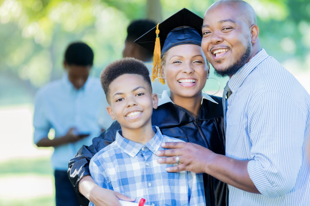 studentsupport1 Antioch University Smiling graduate in cap and gown with family at an outdoor celebration