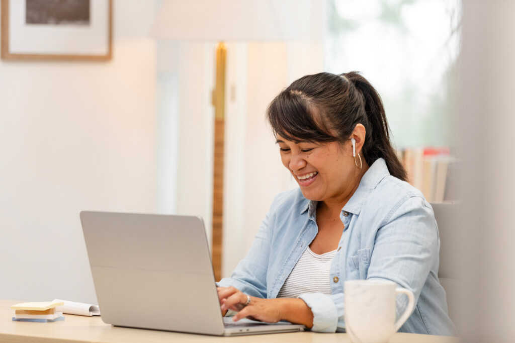 studentsupport3 Antioch University Woman smiling while working on a laptop at a desk