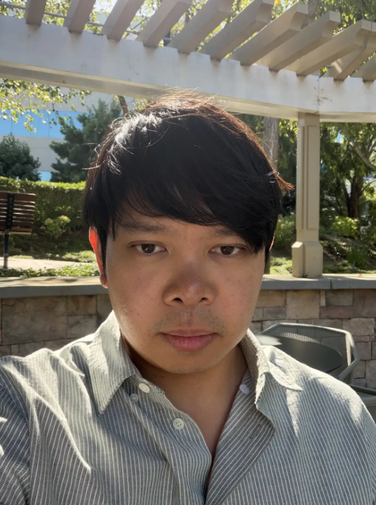 portrait of a man with dark hair in a grey button up shirt