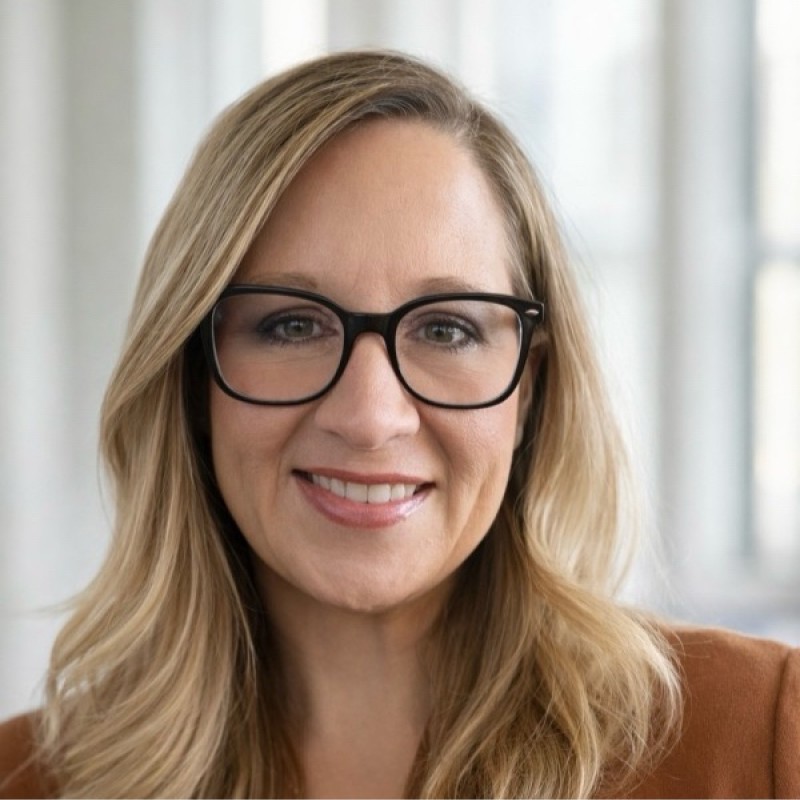 Liz CarsonMurphy Antioch University a blonde haired woman in glasses smiling a portrait a woman in an orange suit posing for a photo