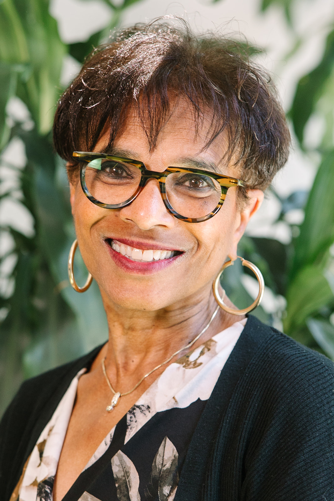 a woman smiling pink lipstick glasses floral blouse a woman smiling outside