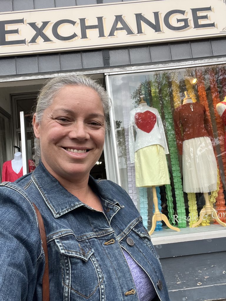 a woman posing in front of a store a woman smiling in a jean jacket