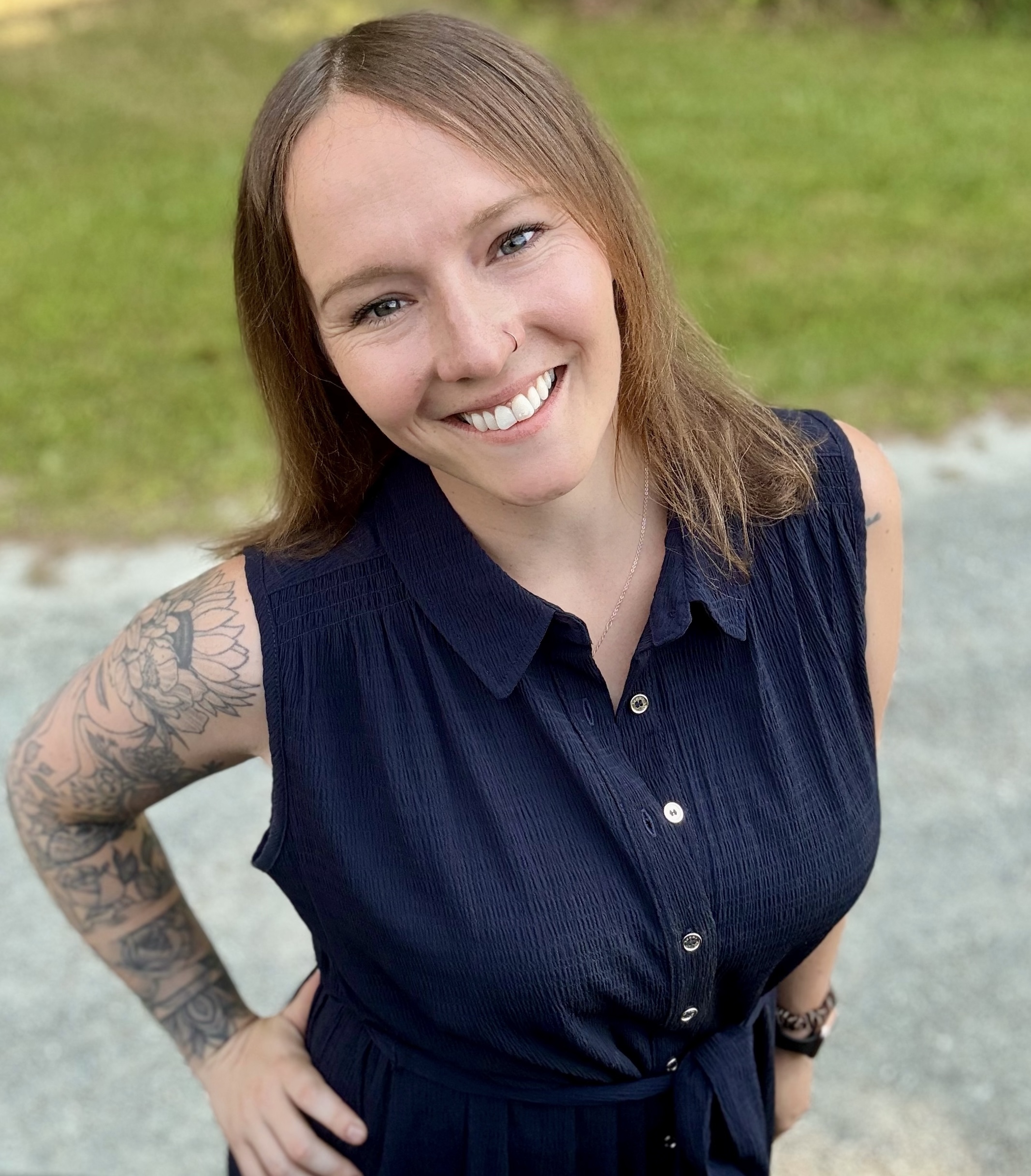 ToriBenson Antioch University a woman with light brown hair in a blue button up blouse and an arm tattoo