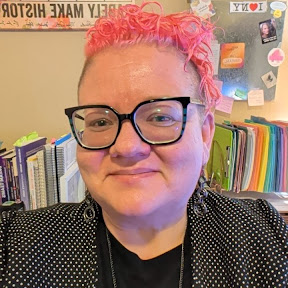 portrait of a woman with pink hair in a black suit close up of a woman smiling with black glasses and pink hair